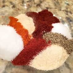 several different types of spices are in a bowl on the counter top, including red, white and brown