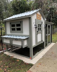 a small chicken coop with a metal roof and windows on the side of the building