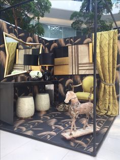 a yellow chair sitting in front of a mirror next to a table with a lamp on it