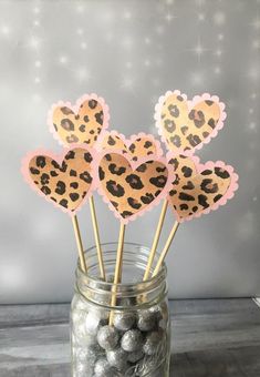 four heart shaped cake toppers in a mason jar filled with chocolate balls and candy