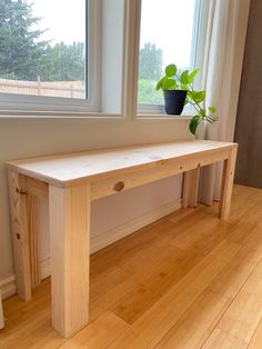 a wooden bench sitting in front of a window next to a vase with a plant on it