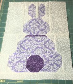 a purple and white quilted bunny sitting on top of a cutting board