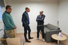 three men standing in an office talking to each other