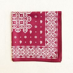 a red and white bandana with an intricate design on the front, hanging from a wall