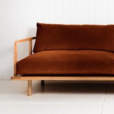 a brown couch sitting on top of a white floor next to a wooden frame chair