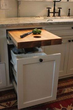 a kitchen with white cabinets and wooden cutting board