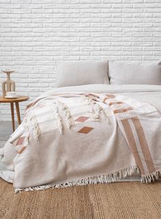 a bed with a blanket on top of it next to a wooden table and chair