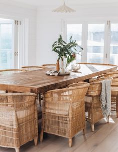 a dining room table with wicker chairs and a potted plant on the table