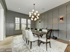 a dining room table with white chairs and a chandelier hanging from the ceiling