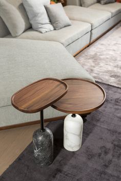 two wooden tables sitting on top of a carpeted floor next to a gray couch