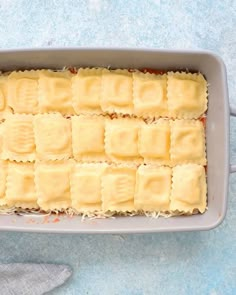 an uncooked casserole dish filled with ravioli and cheese