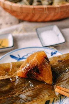 some food on a plate with chopsticks next to it and a bowl in the background