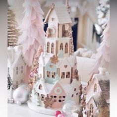 a white shelf topped with pink and gold christmas decorations on top of a wooden table