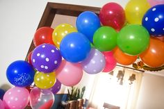 a bunch of balloons that are hanging from a ceiling in a room with a mirror on the wall