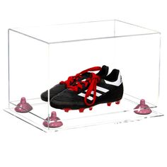 a pair of soccer cleats in a clear acrylic case with red laces