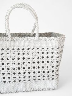 a white basket with black dots on the handles and handle is shown in front of a white background