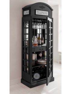 a black phone booth with liquor bottles and glasses on it's shelves in a white room