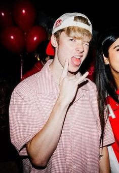 two people standing next to each other with red balloons in the background and one person making a funny face