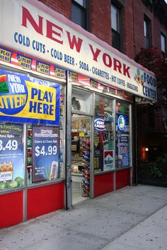 a store front with signs and advertisements on the side of it's windows that read new york, cold cuts, cold beer, soda, games, hot coffee, and more