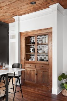 a dining room table with chairs and a china cabinet in the corner next to it