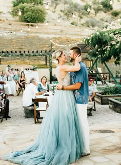 a bride and groom sharing a first dance at their outdoor wedding reception in the mountains