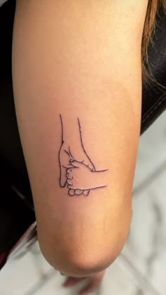 a woman's foot with a small tattoo on her left leg, holding the hand of another person