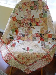 a quilted chair sitting on top of a hard wood floor next to a window