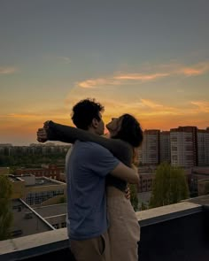 two people embracing each other while the sun is setting in the sky behind them,