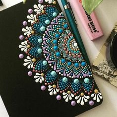 a notebook with beaded designs on it next to a pen and some other items