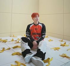 a boy sitting on the floor with bananas all over his feet and hands in front of him