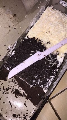 a knife that is laying on top of a cake in a pan with white frosting and black sprinkles