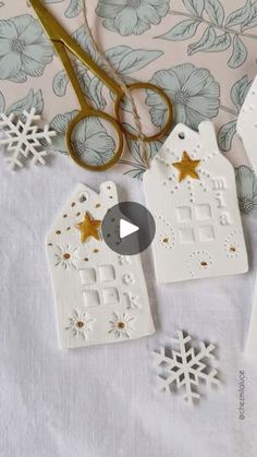 some paper snowflakes and scissors are laying on a table with white fabric, one has gold stars