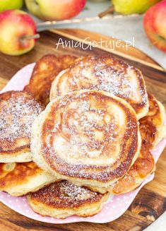 pancakes on a plate with powdered sugar and apples in the backgroung