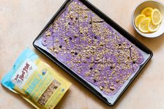 a pan filled with granola next to a bowl of lemons and a bag of chips