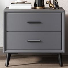 a grey dresser with two drawers and a black vase sitting on it's side