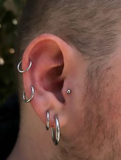 a man with two silver hoops on his ear and one is wearing a nose ring