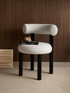 a white chair sitting on top of a wooden floor next to a book shelf with books