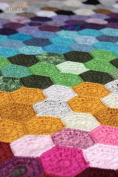 a multicolored crocheted blanket is laying on the floor