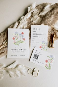 the wedding stationery is laid out on top of some feathers and paper with buttons