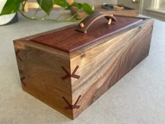 a wooden box sitting on top of a table next to a potted green plant