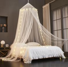 a white canopy bed with fairy lights on it