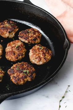 some meat patties are cooking in a skillet