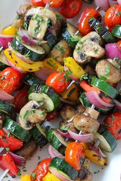 a white plate topped with skewered vegetables and meat