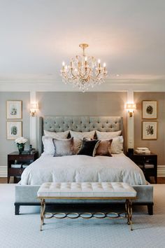 a bedroom with a large bed, chandelier and two lamps on the wall