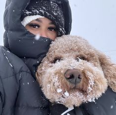 a woman is hugging her dog outside in the snow while it's covered with snow