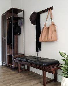 a bench with a purse hanging from it's back and coat rack in the background