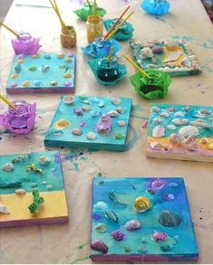 some little boxes that are sitting on a table covered in seaweed and seashells