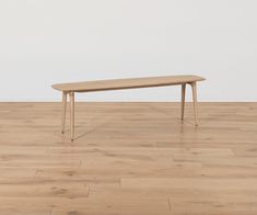 a wooden table sitting on top of a hard wood floor next to a white wall