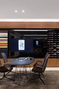 a table with four chairs around it in front of a television and wine racks on the wall