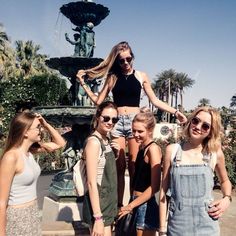 four girls are standing in front of a fountain